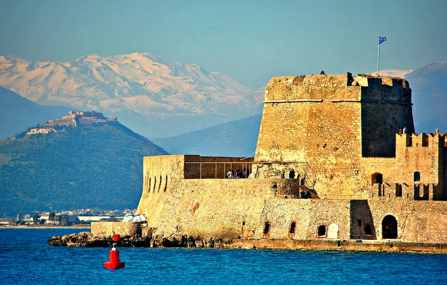 castello-di-nauplia-fortificato-davanti-al-mare-blu-dietro-il cielo-e-le-montagne-celesti
