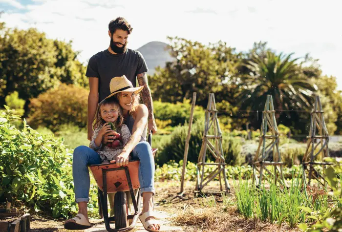 mamma-e-figlio-seduti-su-una-carrioletta-il-papà-dietr-di-loro-in-una-campagna-verde