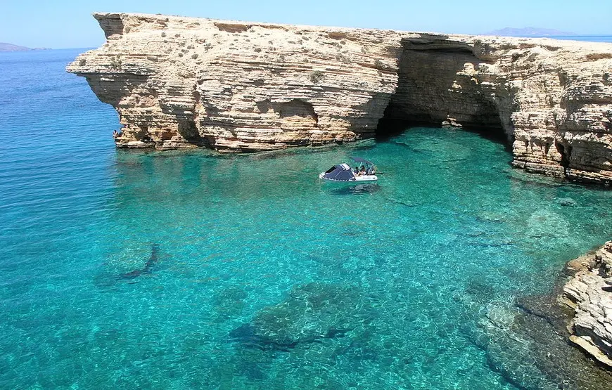 mare-turchese-e-trasparente-aridosso-di-un-promontorio-roccioso-in-mezzo-una-barchetta