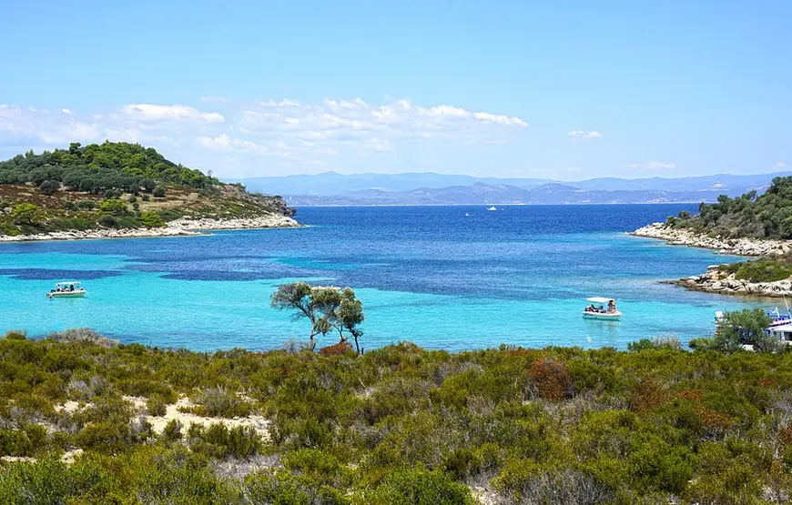 mare-turchese-dentro-un-insenatura-intorno-coste-rocciose-ricoperte-di-verde