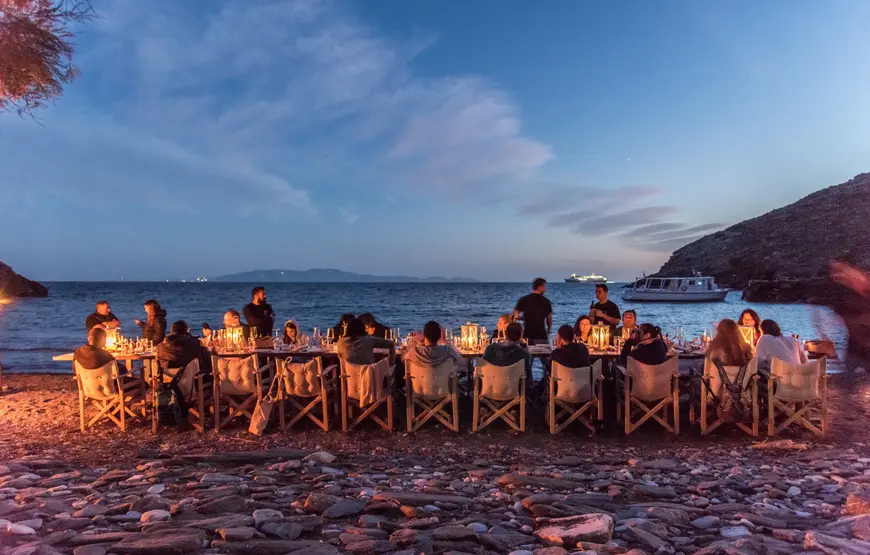 tavolata-sulla-spiaggia-con-il-mare-blu-dietro-illuminati-da-candele
