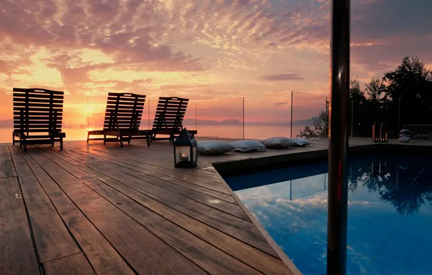 terrazza-di-legno-con-piscina-zona-attico-con-due-sdraio-che-guardano-il-tramonto