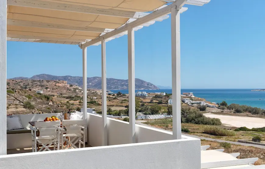 dalla-terrazza-bianca-di-un-hotel-dove-ci-e-un-tavolo-apparecchiato-si-vede-il-paesaggio-di-kimolos-fino-al-mare