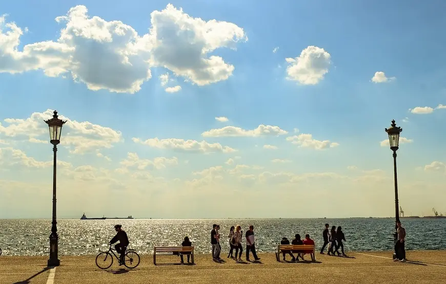 lungomare-di-salonicco-con-passanti-a-piedi-e-in-bici-qualche-panchina-il-mare-davanti