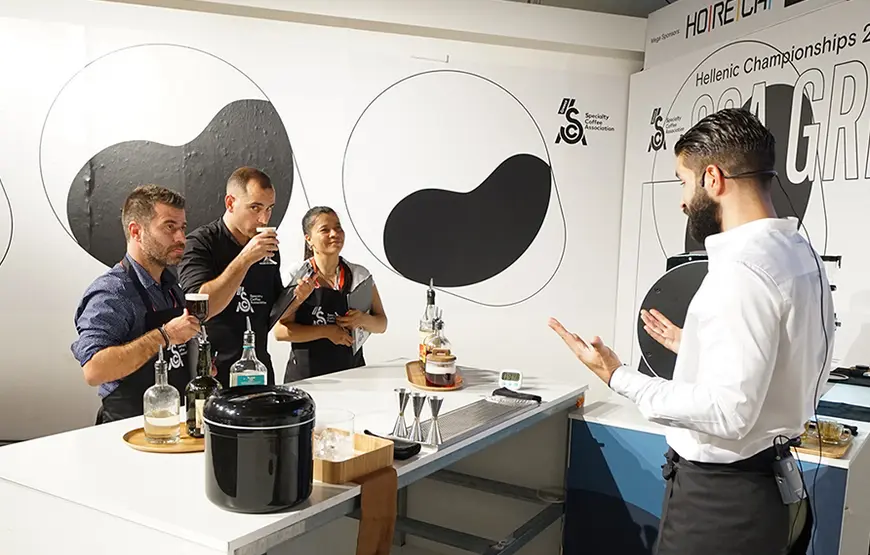 in-una-sala-bianca-con-simboli-dello-yin-e-yang-alle-pareti-ci-sono-tre-persone-che-stanno-degustando-un-prodotto-e-un-relatore-che-spiega