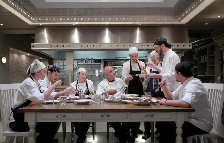 chef-intorno-a-un-tavolo-mentre-assaggiano-dei-piatti