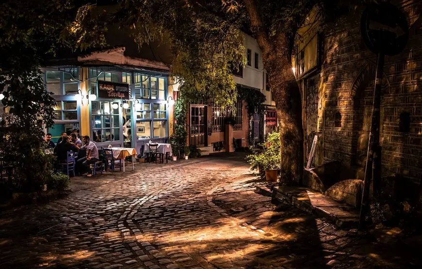 esterno-di-una-ouzeria-a-asalonicco-sotto-gli-alberi-illuminata-di-sera-tutta-a-vetri