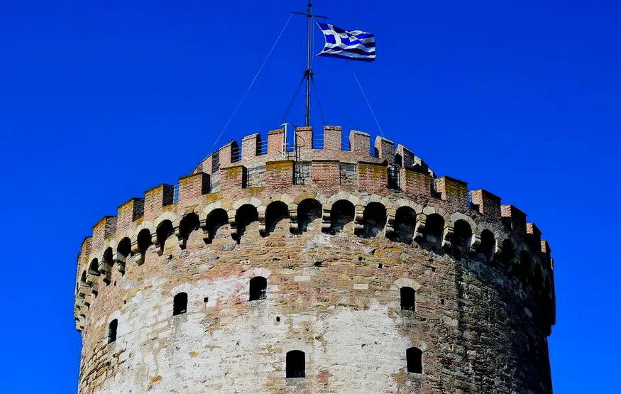 particolare-della-torre-bianca-di-salonicco-la-merlatura-in-alto-e-la-bandiera-greca-che-sventola-alta-in-cima