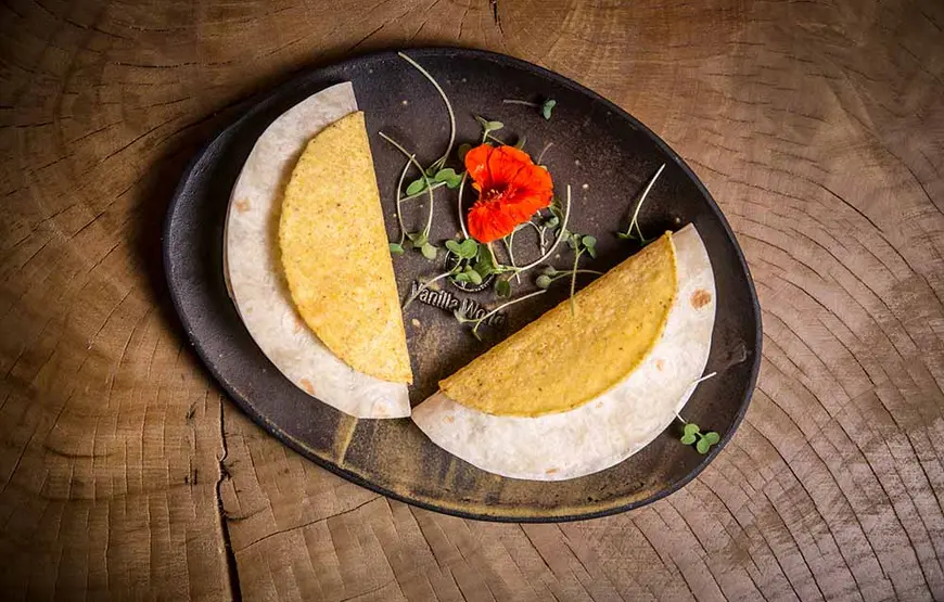 piatto-di-salonicco-due-crepe-a-mezza-luna-che-formano-un-occhio-di-bue-aperto-a-v-con-un-papavero-e-delle-erbette-a-fare-da-decorazioni