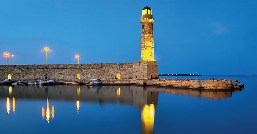 faro-di-heraklion-in-mezzo-all-acqua-illuminato-di-giallo-con-il-sole-tramontato