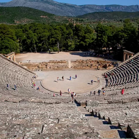 TEATRO-DI-EPIDAURO-VISTO-DALL-ULTIMA-GRADINATA-GIU-VERSO-LA-CAVEA-DIETRO-UNA-COLLINA-VERDE