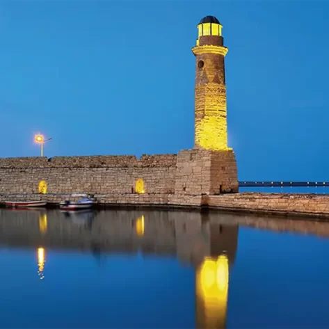 il-faro-illuminato-di-giallo-si-riflette-sul-mare-blu