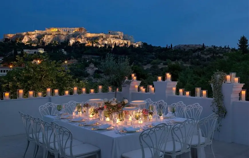 cena-romantica-tavolo-tutto-bianco-e-candele-accese-di-fronte-all-acropoli-di-atene-illuminata-di-sera