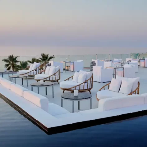 una-terrazza-sulla-piscina-con-poltrone-tonde-e-dietro-tavoli-ristorante