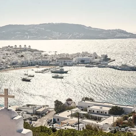 vista-di-mykonos-con-le-barche-in-mezzo-al-mare-e-le-case-bianche-lungo-la-costa
