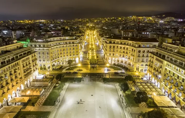 PIAZZA-ARISTOTELOU-A-SALONICCO-CON-GRANDE-PIAZZALE-E-EDIFICI-CONCAVI-TRA-CUI-PARTE-UNA-STRADA-TUTTA-ILLUMINATA-VERTICALE