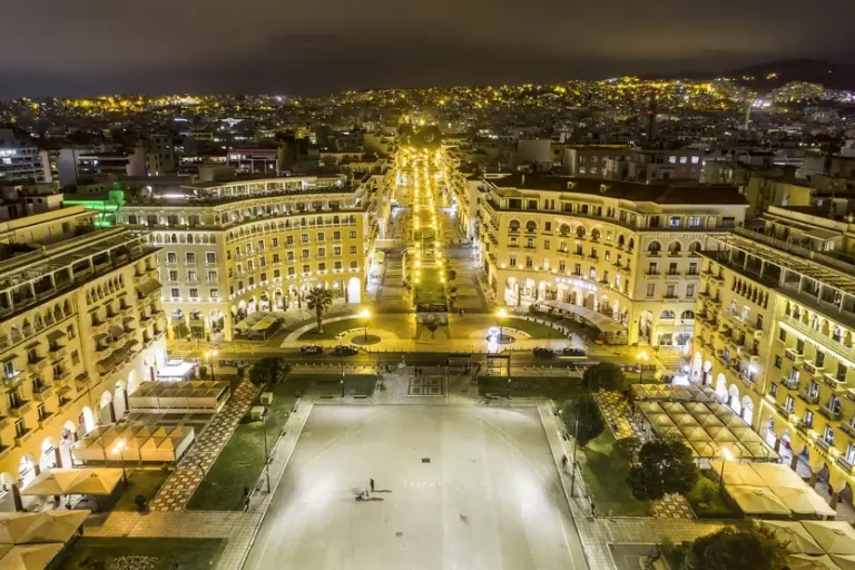 PIAZZA-ARISTOTELOU-A-SALONICCO-CON-GRANDE-PIAZZALE-E-EDIFICI-CONCAVI-TRA-CUI-PARTE-UNA-STRADA-TUTTA-ILLUMINATA-VERTICALE